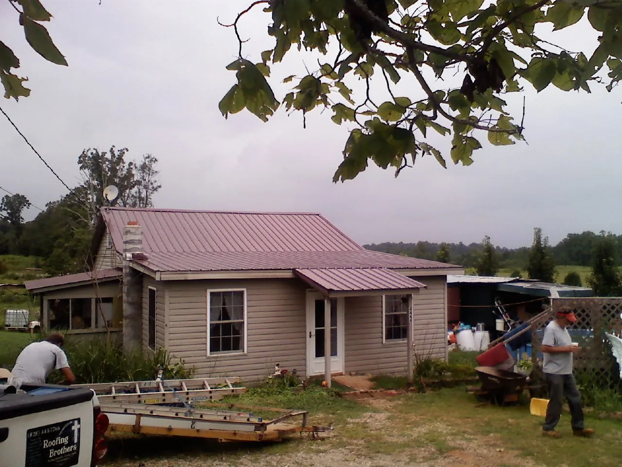 Crew finishing a mauve metal roof on a small farmhouse in Crompond