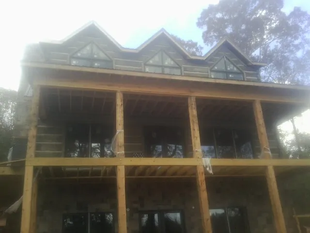 Dormers and porch framing on a large log home under construction — Roof Coating work by our crew in Crompond