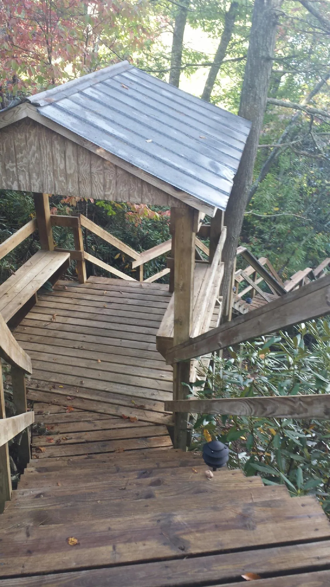 Metal roofed shelter over wooden steps on a wooded walkway — Skylight Repair & Installation work by our crew in Crompond