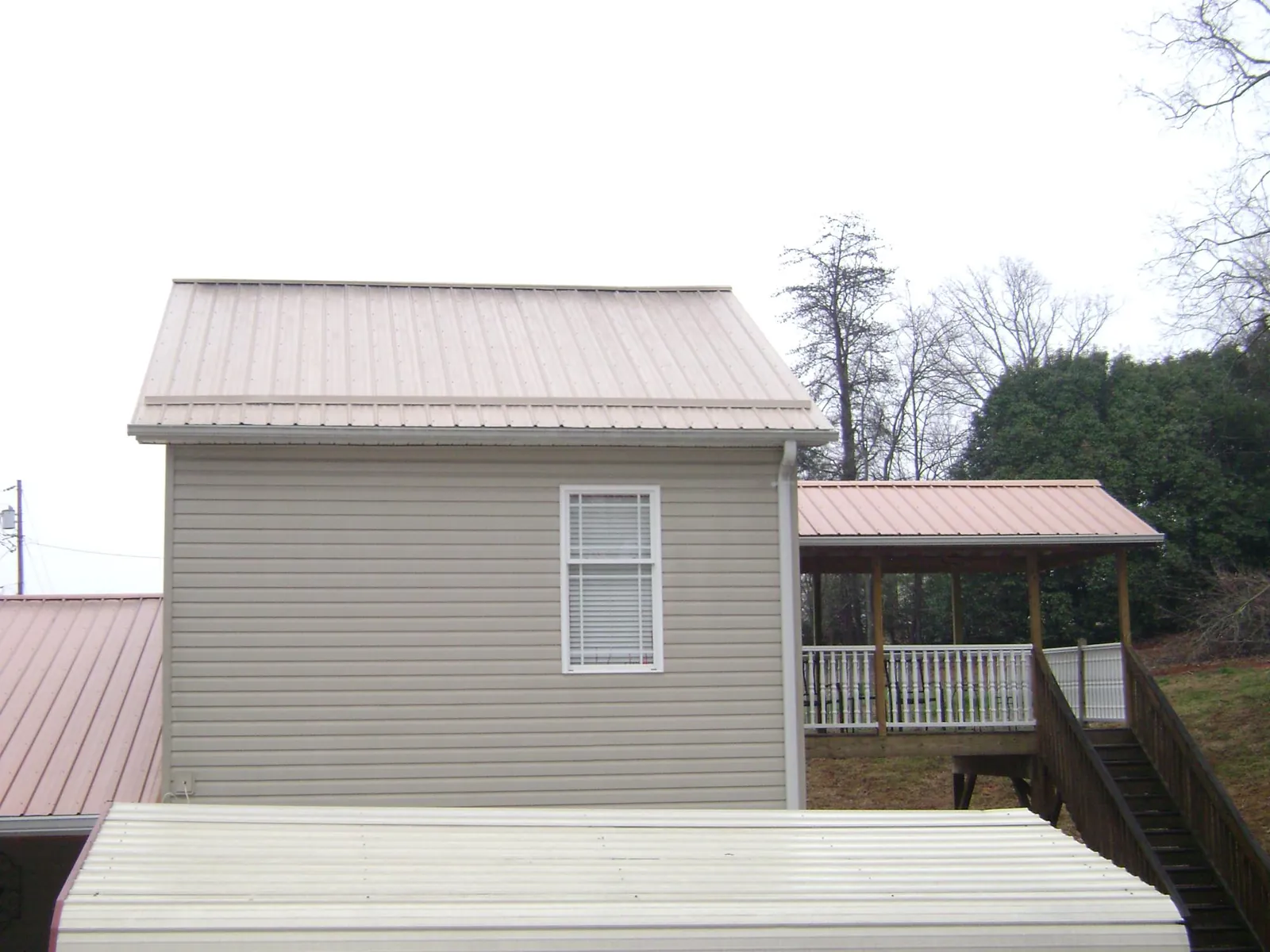 Tan metal roofs on a two story addition and attached porch, from a Roof Replacement job in Crompond