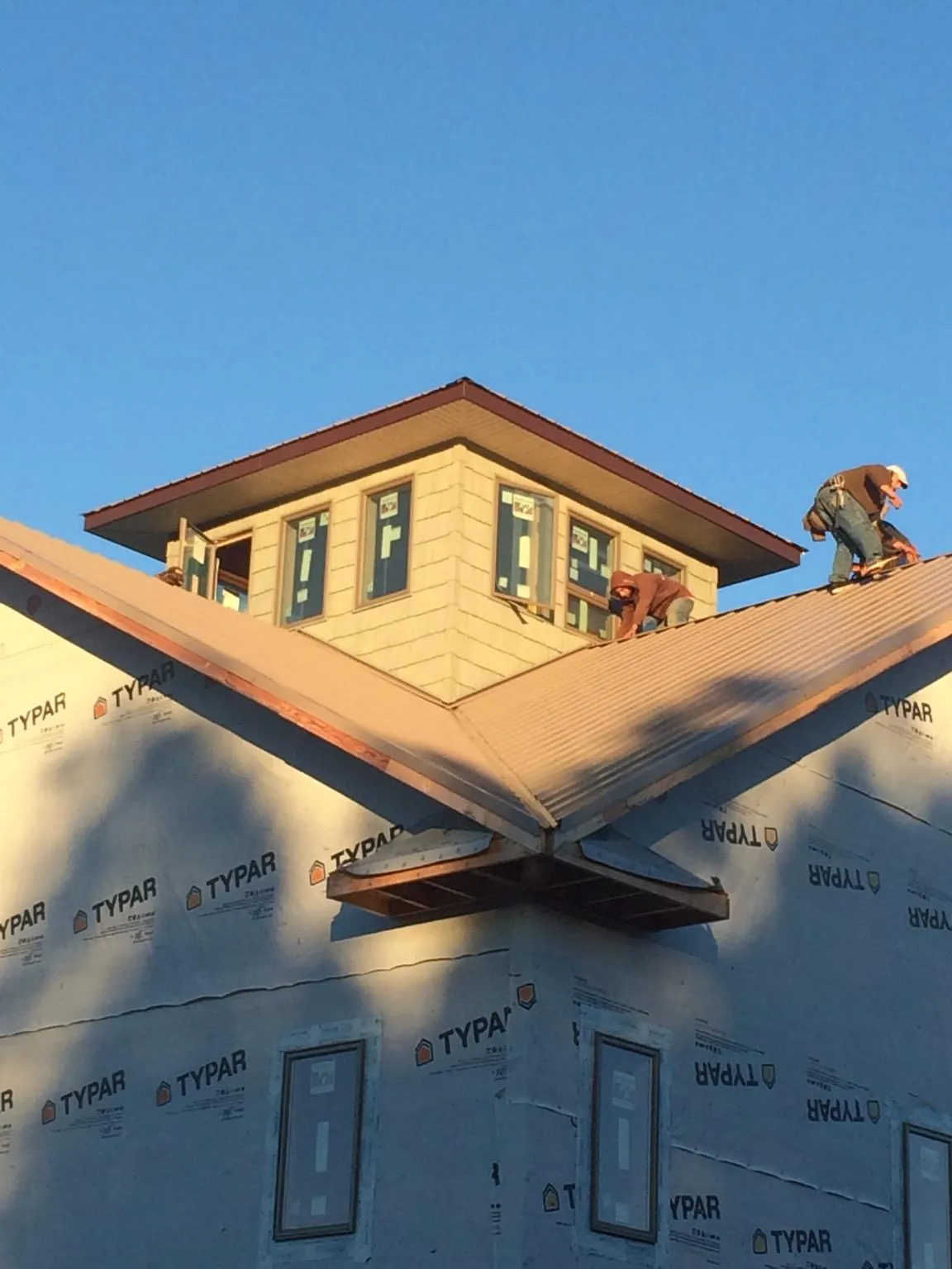 Roofers working around a rooftop cupola on a new metal roof at sunset — Roof Waterproofing in Crompond by Roofing Brothers